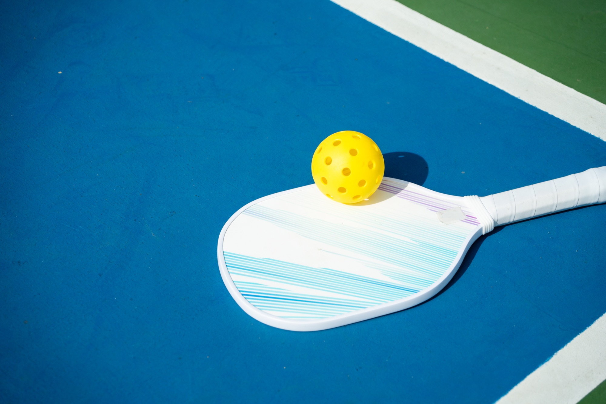 Pickleball paddles and yellow balls ready for a game beside the net