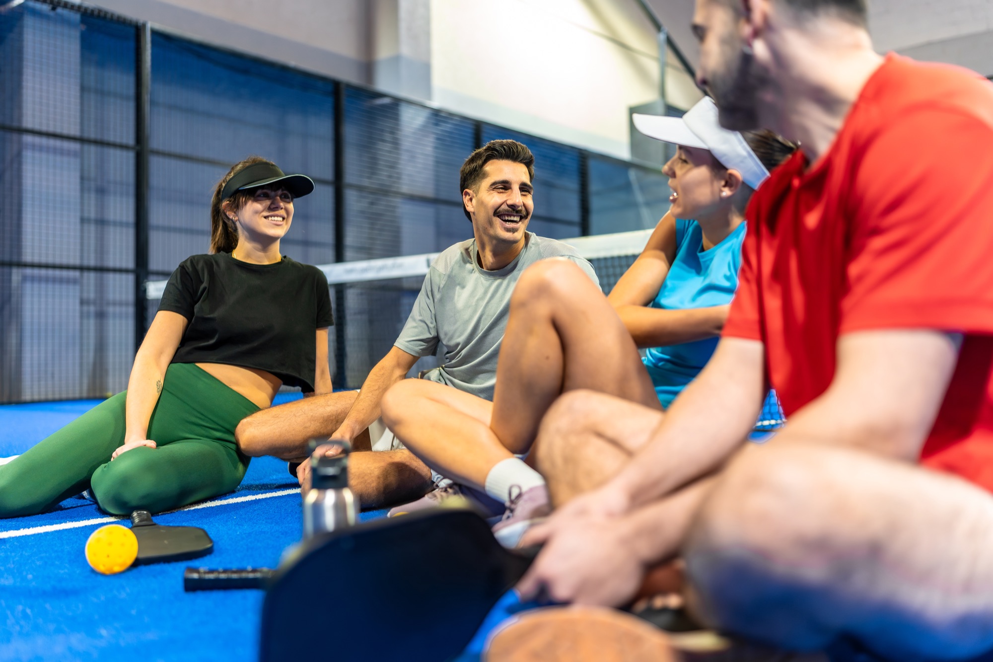 Four friends relaxing courtside with their pickleball paddles