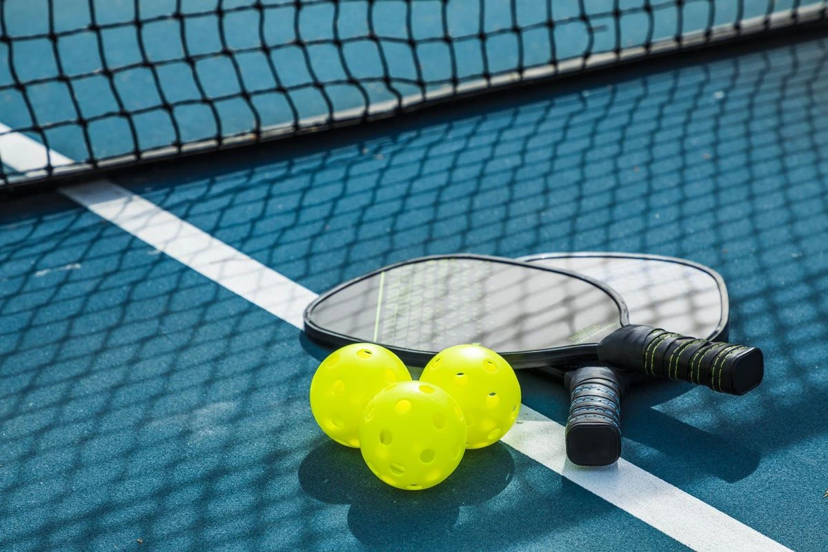 Pickleball paddles and balls on a blue court